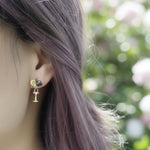 Close-up of an ear wearing a small earring with a blurred floral background