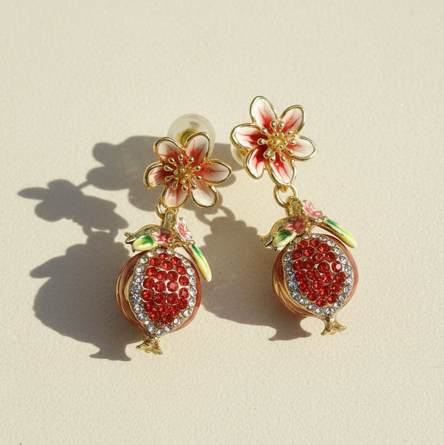 Floral and pomegranate design earrings on a beige background