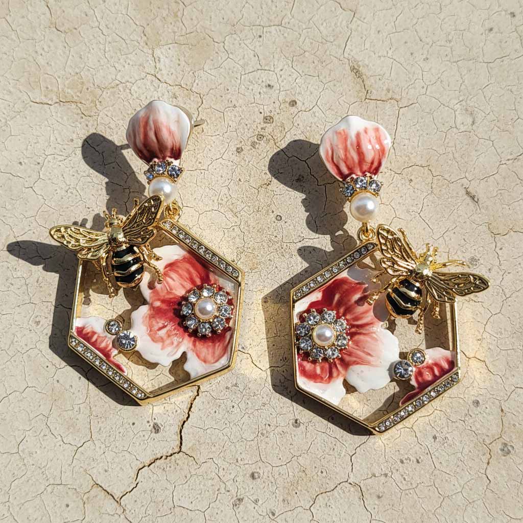 Pair of earrings with floral and bee design on a textured beige background