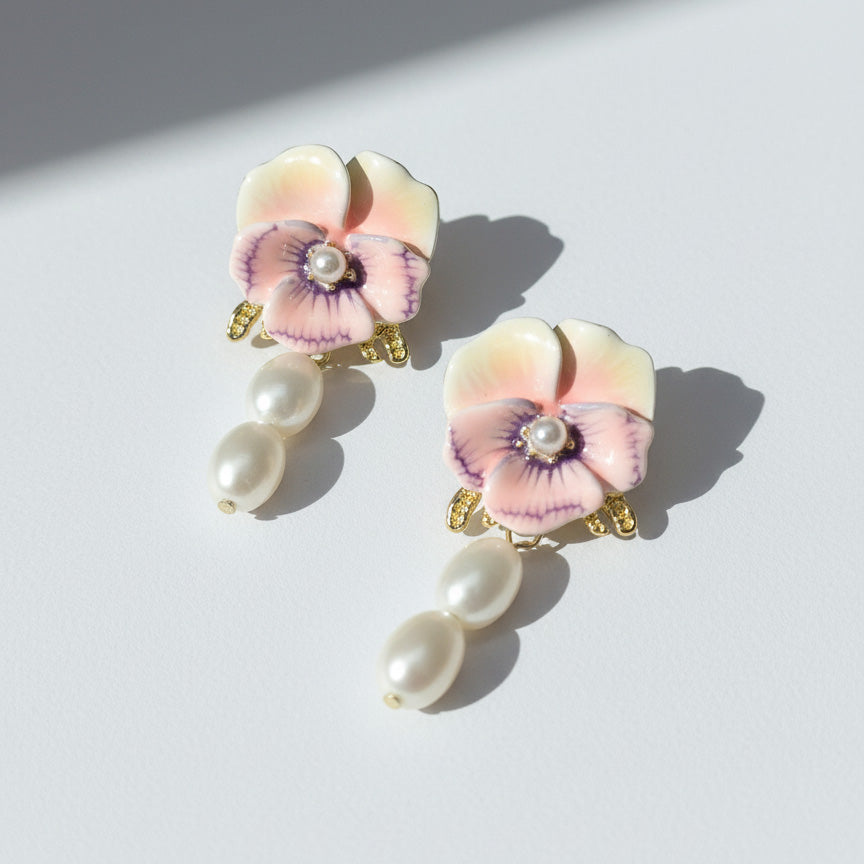 Pair of floral earrings with pearl-like stones on a light background