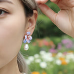 Close-up of a person wearing floral earrings with a blurred garden background