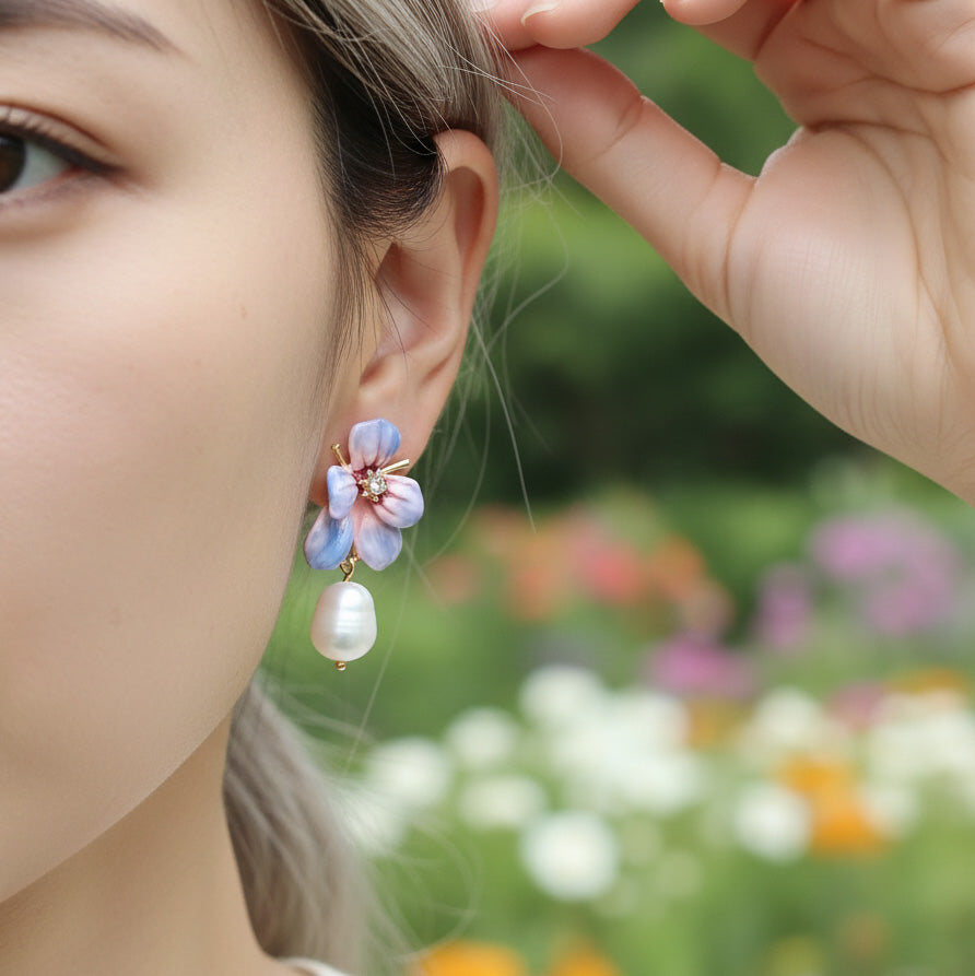 Close-up of a person wearing floral earrings with a blurred garden background