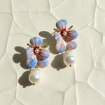 Floral earrings with pearl accents on a textured white surface