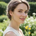 Woman wearing gold earrings with a blurred garden background