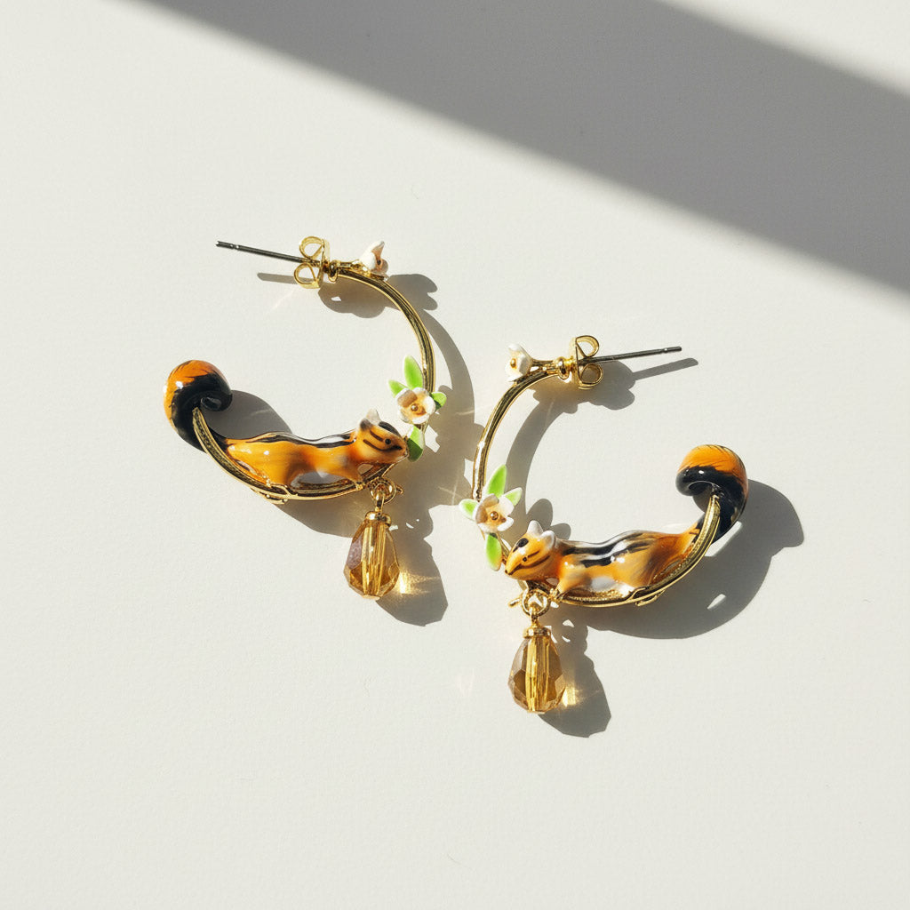 Pair of gold hoop earrings with animal-themed charms on a light background