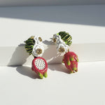 Earrings resembling dragon fruit on a white surface