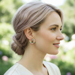Woman wearing colorful floral earrings with a blurred green background