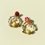 Pair of earrings with floral and chick designs on a beige background