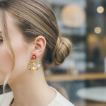 Close-up of a woman wearing colorful floral earrings with a blurred background