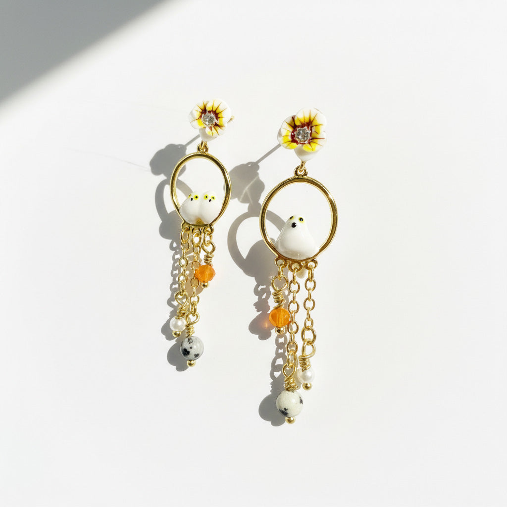 Pair of earrings with floral and chain designs on a white background