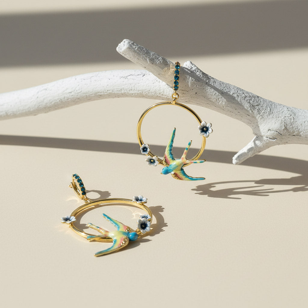 Gold earrings with bird designs on a beige surface