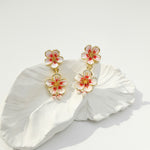 Floral earrings with gold accents on a white petal background