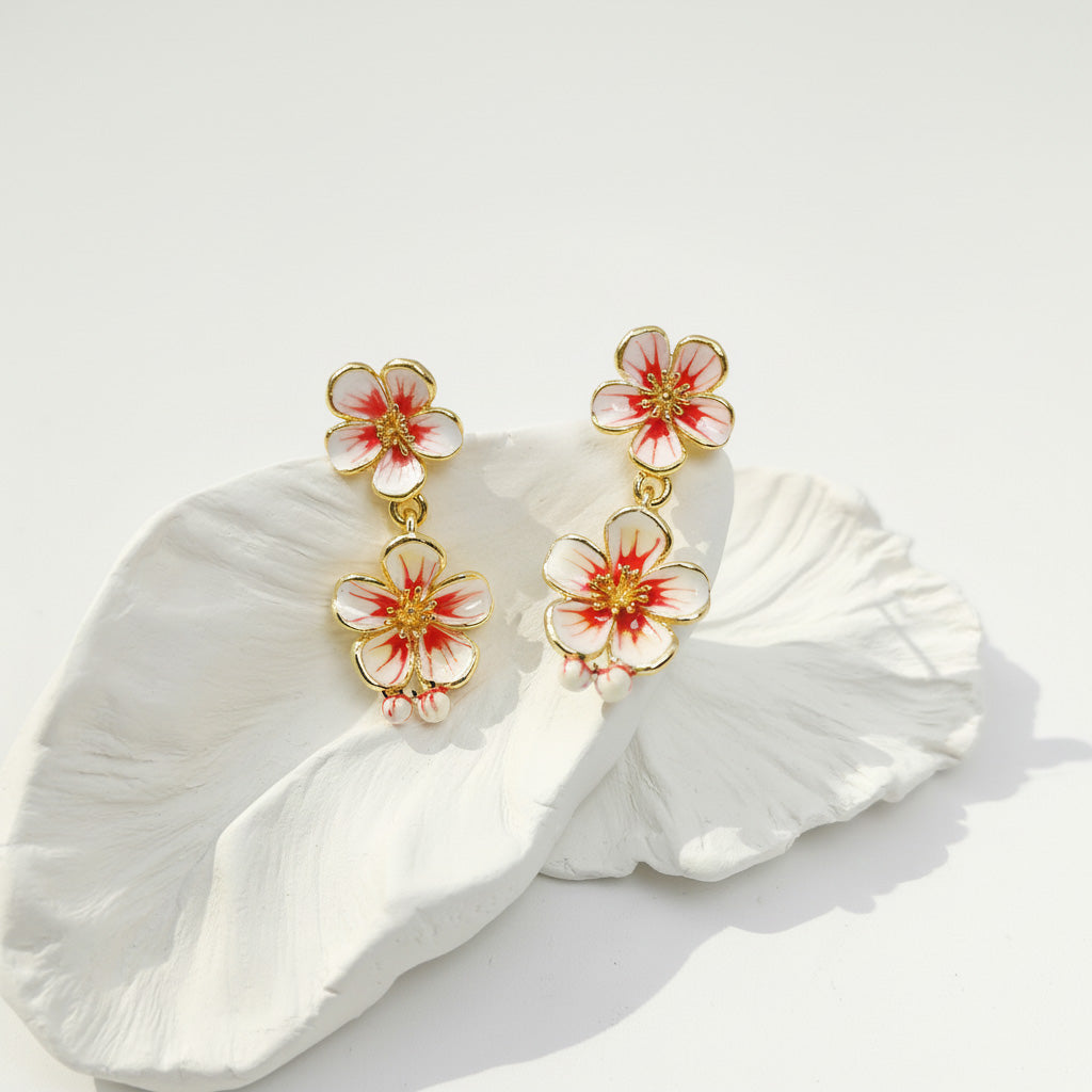 Floral earrings with gold accents on a white petal background