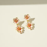 Floral earrings with gold accents on a beige background