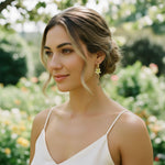 Woman wearing a white dress with floral earrings in a garden setting