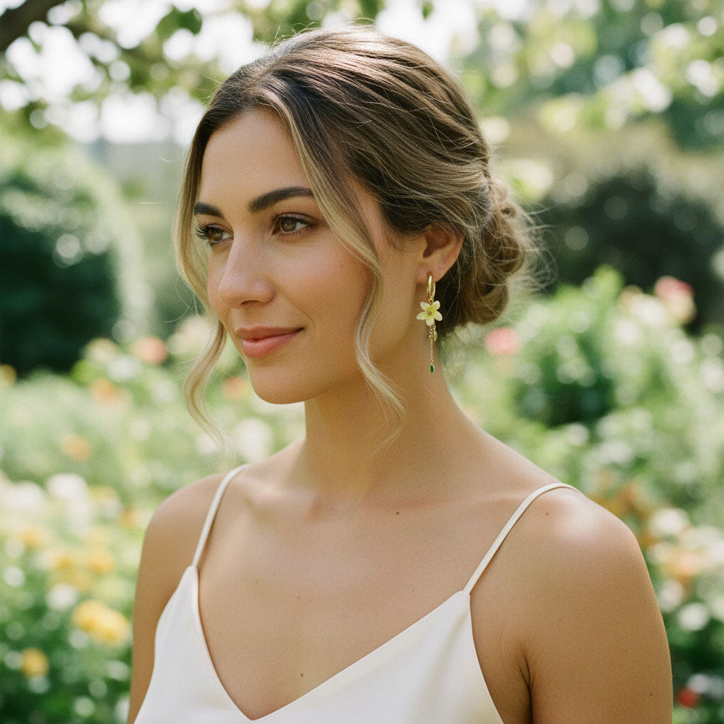 Woman wearing a white dress with floral earrings in a garden setting