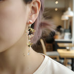 Close-up of a person wearing a decorative earring with a blurred indoor background