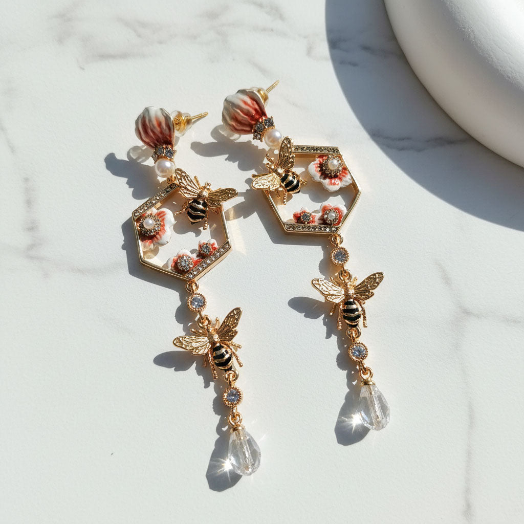 Gold bee earrings with floral details on a light background