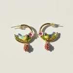 Pair of earrings with bird and flower designs on a light background