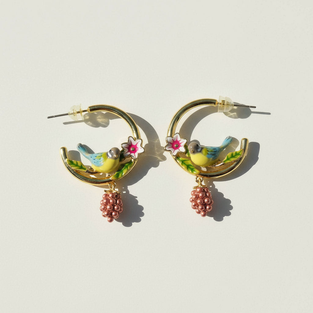 Pair of earrings with bird and flower designs on a light background