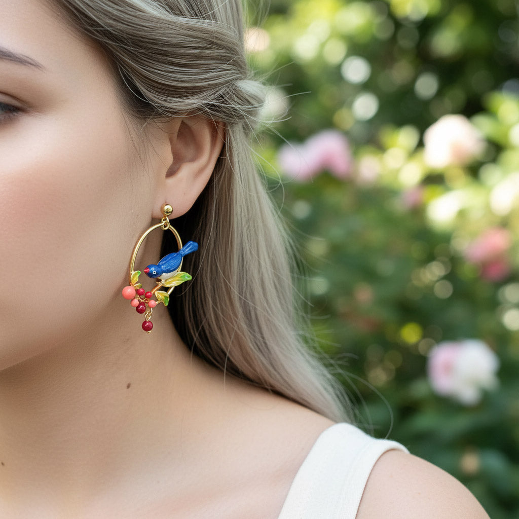 Close-up of a woman wearing colorful hoop earrings with a blurred floral background