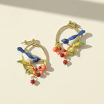 Colorful bird-shaped earrings on a beige background