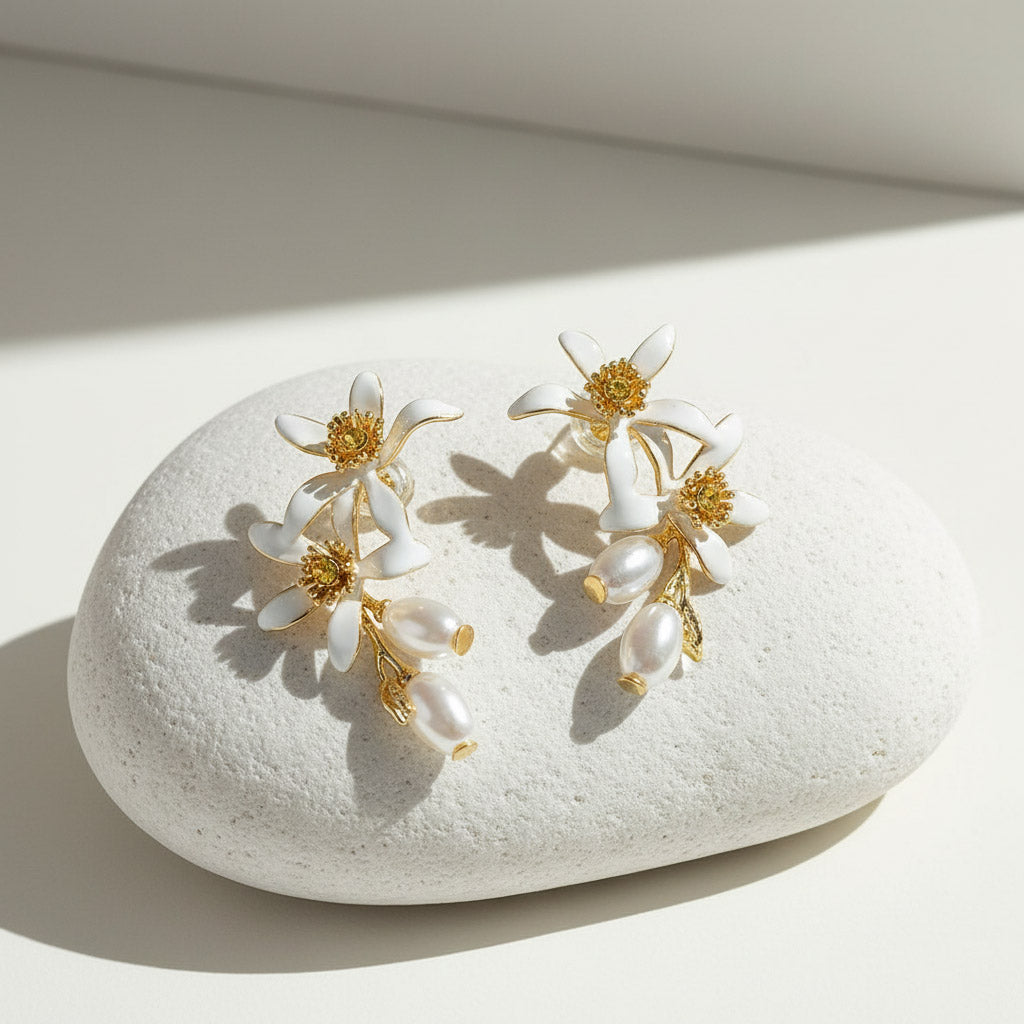 Hand-painted floral pearl earrings resting on white stone.
