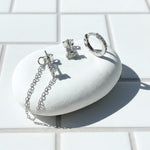 Silver earrings on a white stone surface with a light background