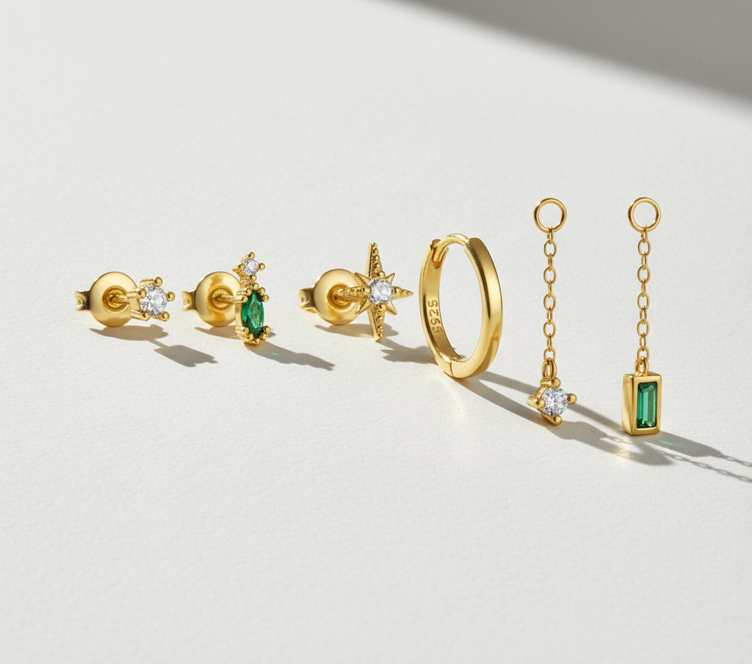 Gold jewelry set with emeralds on a light background