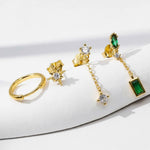 Gold jewelry set with emerald green stones on a white surface