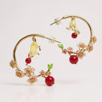 Gold hoop earrings with cherry and flower designs on a white background