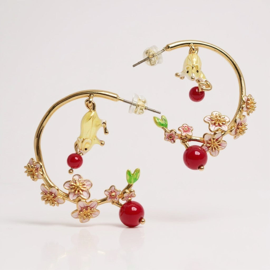 Gold hoop earrings with cherry and flower designs on a white background