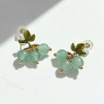 Pair of earrings with green beads and leaf-like elements on a white background