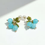 Pair of earrings with turquoise beads and green leaves on a white background