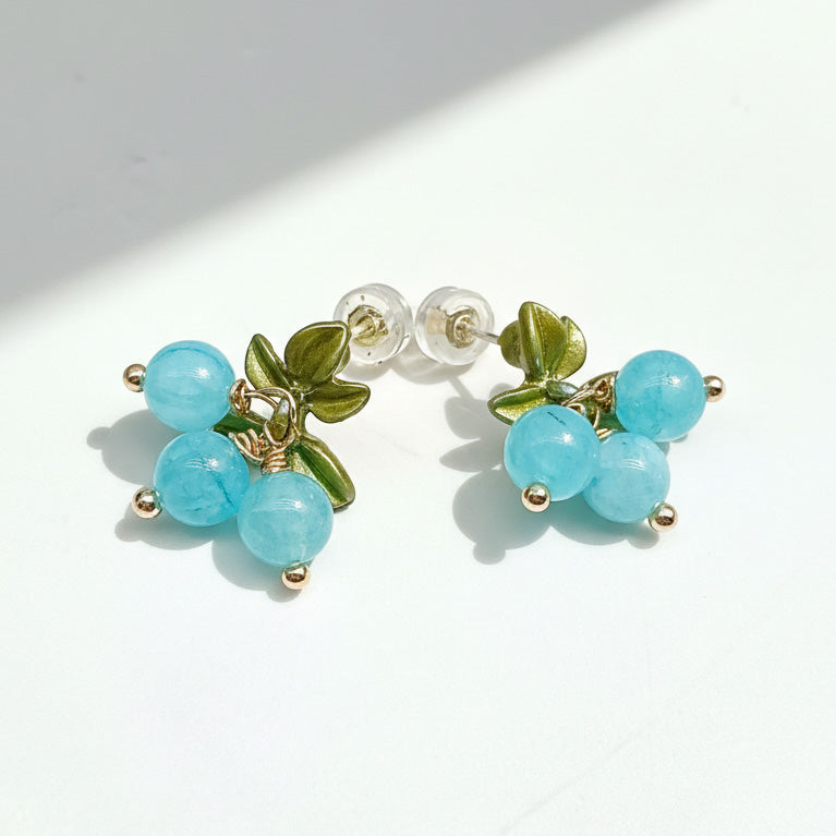 Pair of earrings with turquoise beads and green leaves on a white background