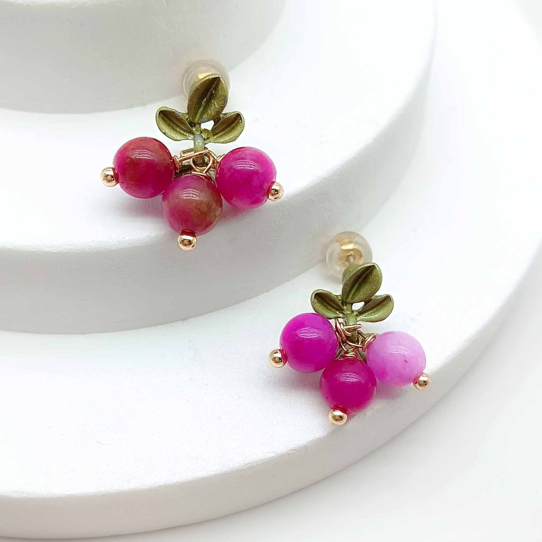 Pair of earrings with pink beads and gold accents on a white background