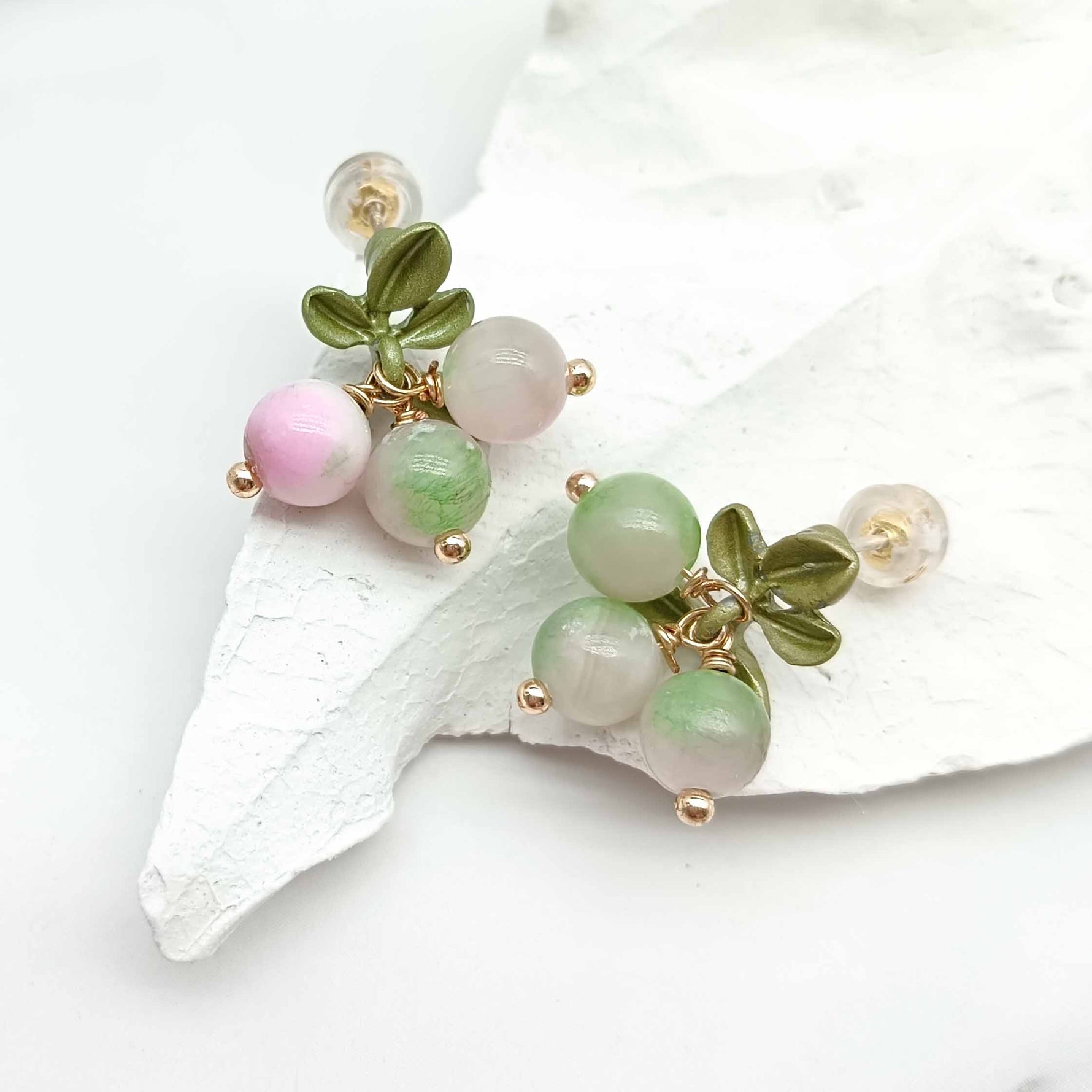 Decorative bracelet with green and pink beads on a white shell background