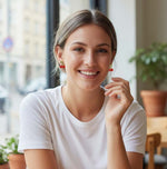 Woman wearing a white shirt with red earrings in an indoor setting