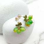 Green beaded earrings on a white stone surface