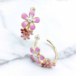 Flower-shaped earrings with pink and gold details on a marble surface