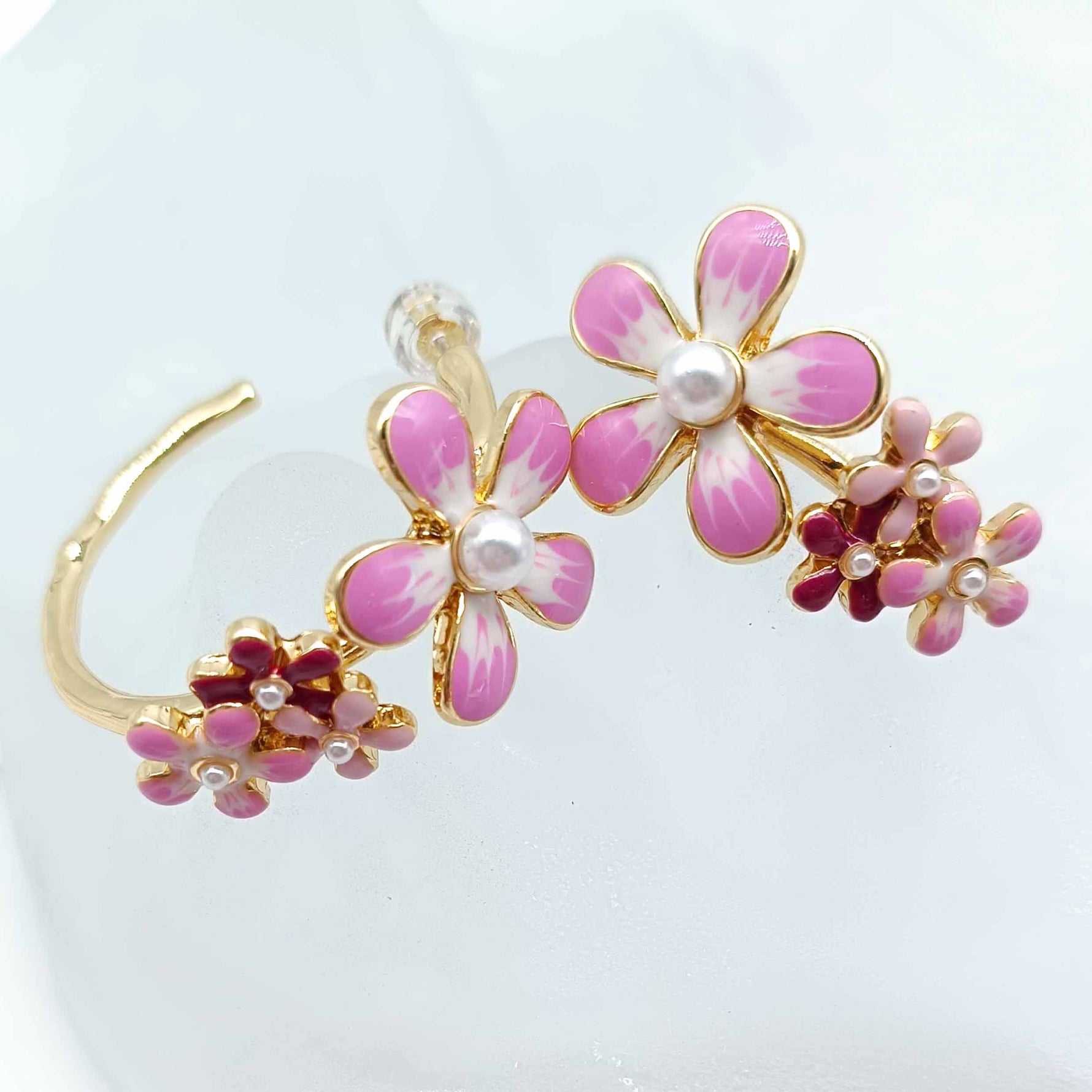 Floral ear cuff with pink flowers and gold accents on a white background