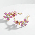 Floral earrings with pink flowers and gold accents on a white background