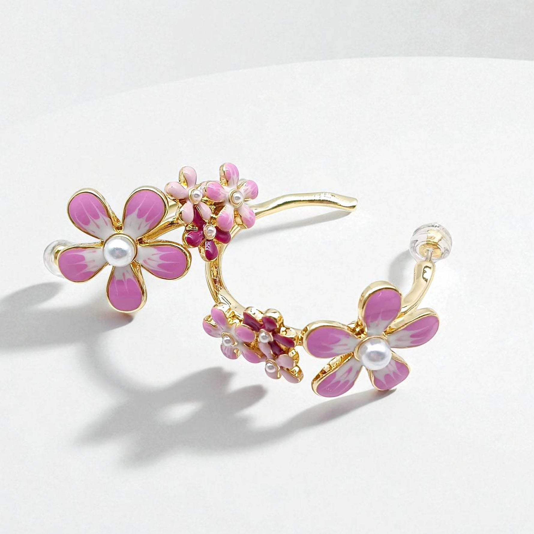 Floral earrings with pink flowers and gold accents on a white background