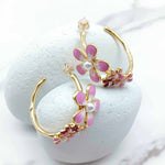 Gold hoop earrings with pink floral designs on a white background
