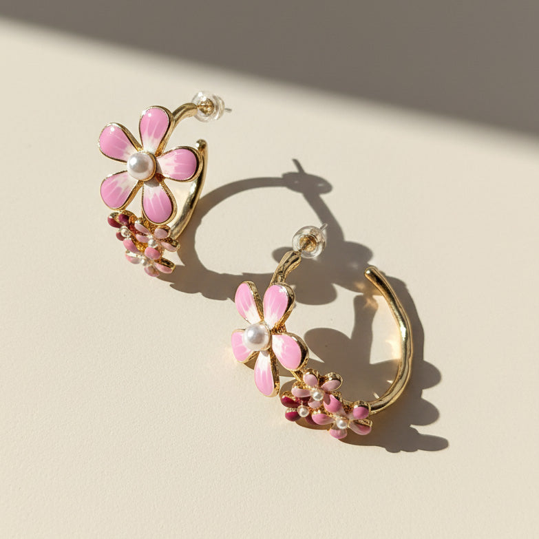 Pair of pink flower-shaped earrings with gold accents on a beige background
