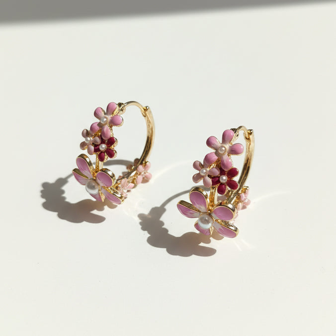 Gold hoop earrings with pink floral and pearl details on a light background