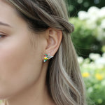 Side view of model wearing hand-painted hummingbird earrings by A2K London, showcasing fine enamel detail.