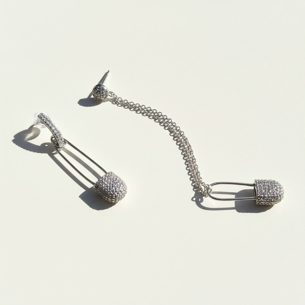 Silver earring with chain and spherical components on a light background