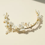 Floral gold tiara with porcelain blooms and pearls under sunlight.