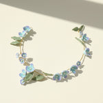 Floral headband with blue flowers and green leaves on a beige background